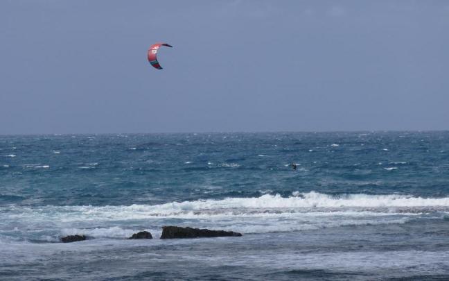 Una persona practica kitesurf en una playa.