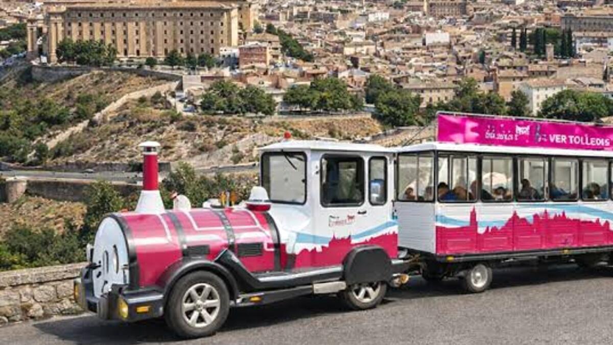 Un tren turístico recorre uno de los miradores de Toledo, con la ciudad al fondo.