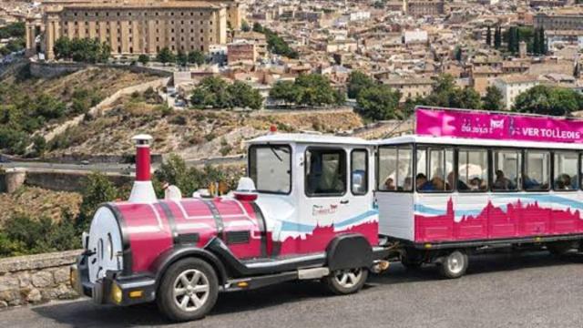 Un tren turístico recorre uno de los miradores de Toledo, con la ciudad al fondo.