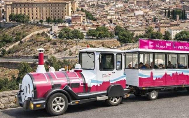 Un tren turístico recorre uno de los miradores de Toledo, con la ciudad al fondo.