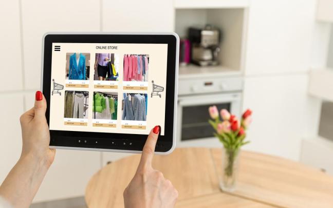 Una mujer utiliza una tablet para comprar ropa online. Una mujer utiliza una tablet para comprar ropa online.
