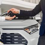 Persona recibiendo las llaves de un coche después de haberlo comprado.
