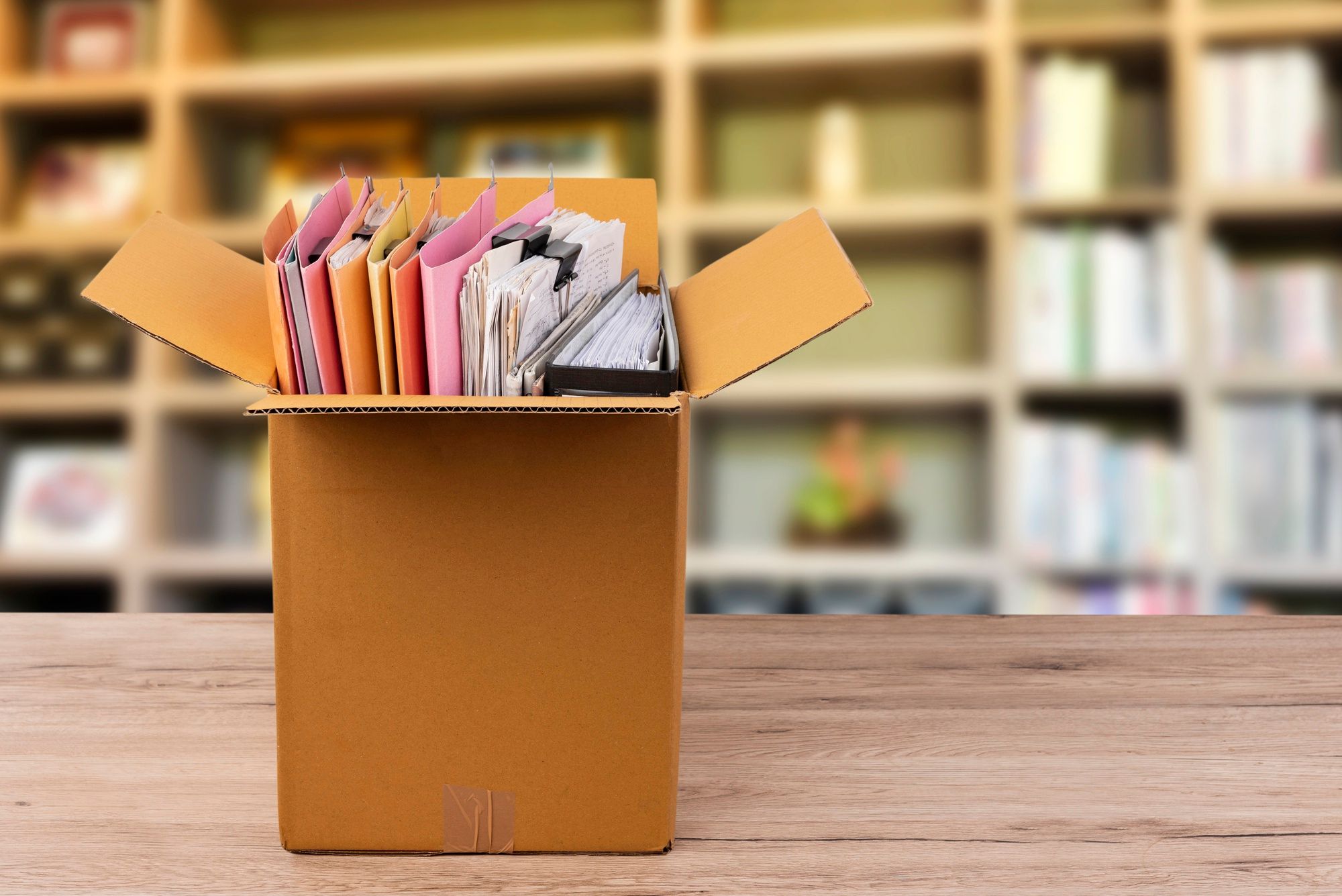 Documentos ordenados en carpetas en una caja de cartón.