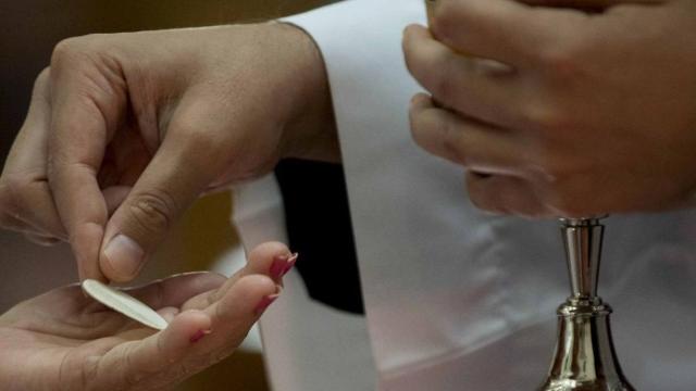 Un sacerdote da la comunión durante una celebración