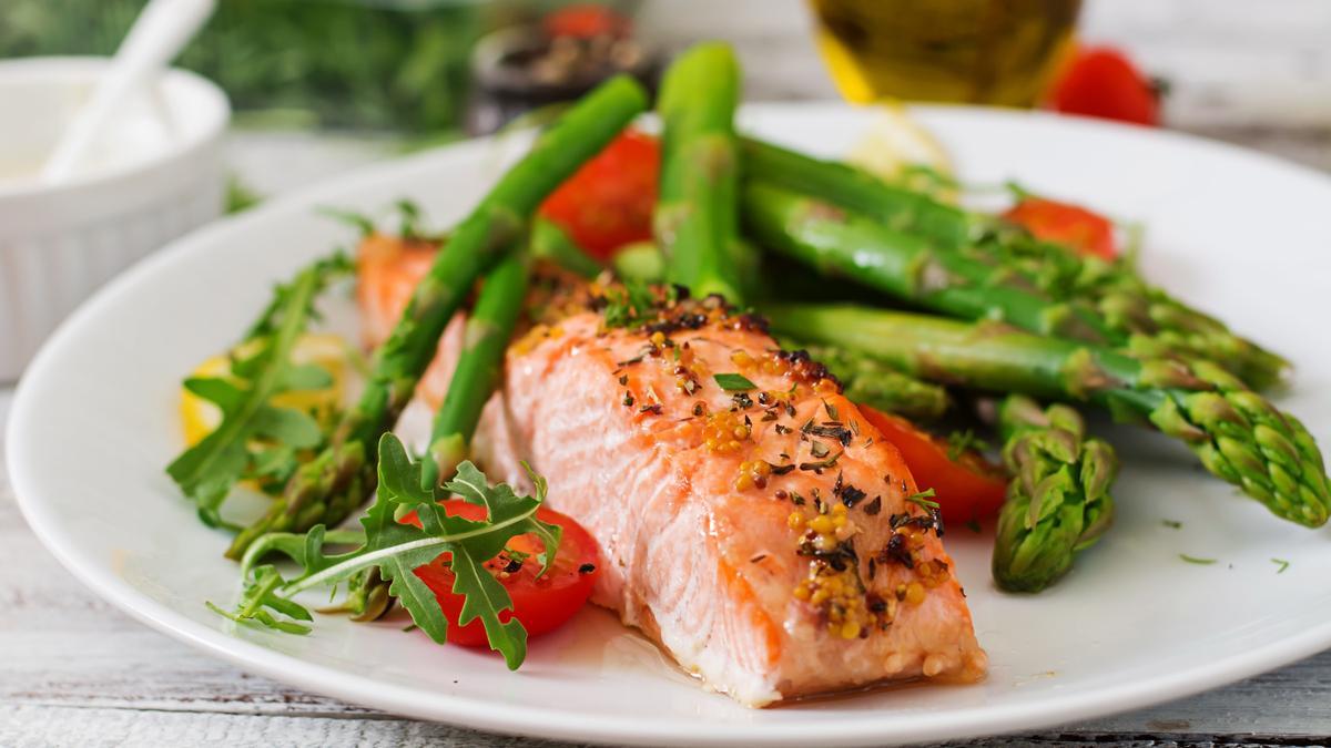 Lomo de salmón acompañado con espárragos verdes y tomate.
