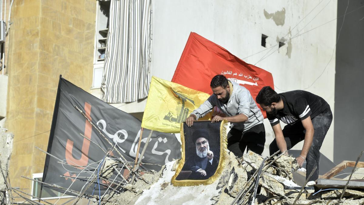 Libaneses portando carteles con la imagen de Hasán Nasrala sobre los escombros de los bombardeos israelíes.