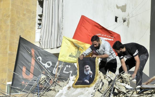 Libaneses portando carteles con la imagen de Hasán Nasrala sobre los escombros de los bombardeos israelíes.
