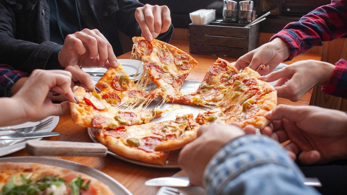 Cuatro amigos comparten una pizza en un restaurante.