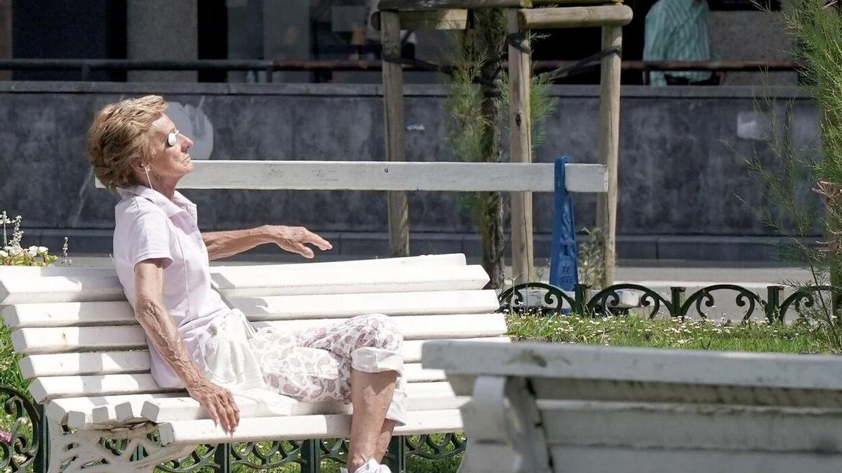 Una mujer toma el sol en un banco de Donostia.