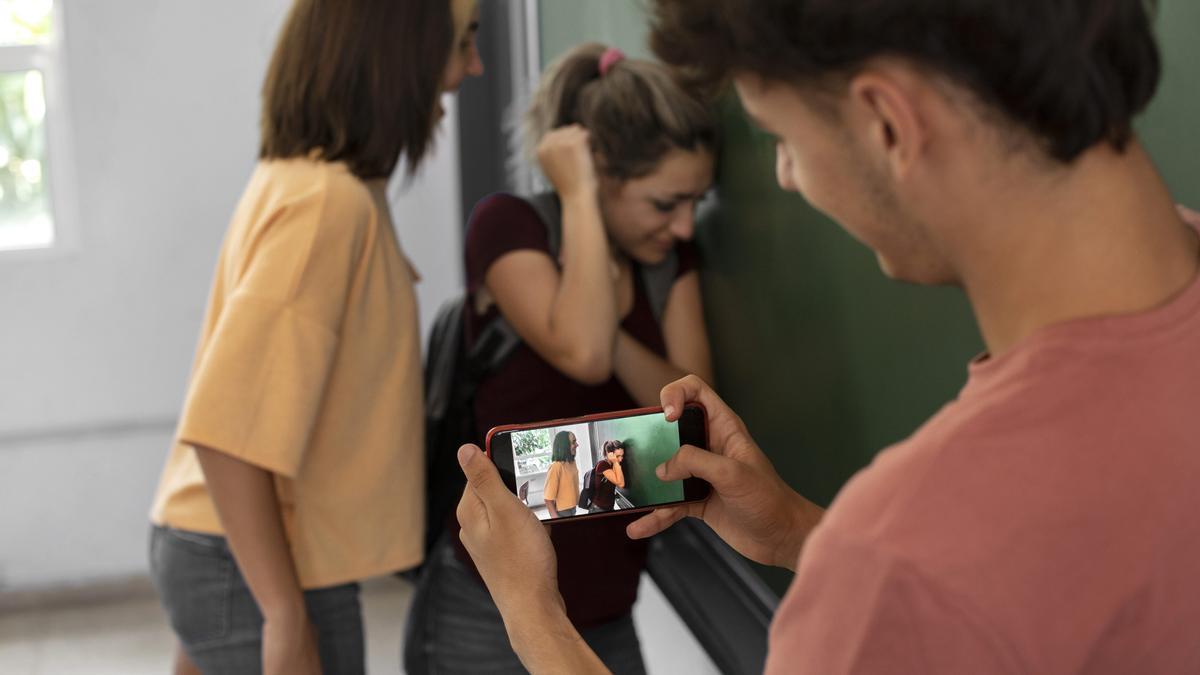 Un joven graba con su móvil como una adolescente acosa a una compañera de clase.
