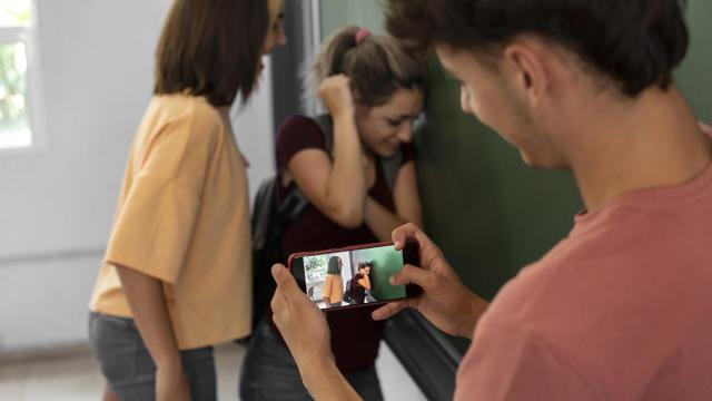 Un joven graba con su móvil como una adolescente acosa a una compañera de clase.
