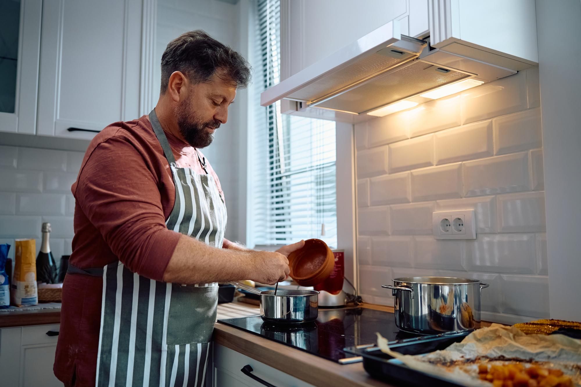 Un hombre prepara la comida con la campana encendida.