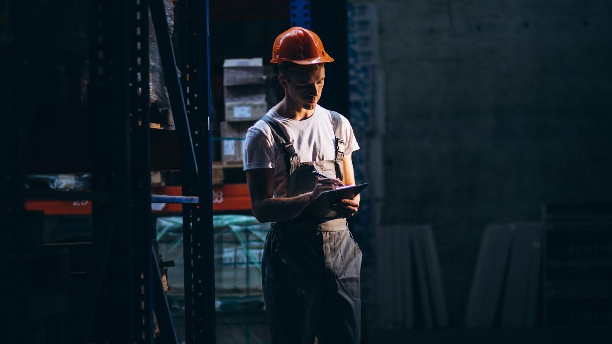 Un trabajador toma notas en un bloc durante un turno de noche.