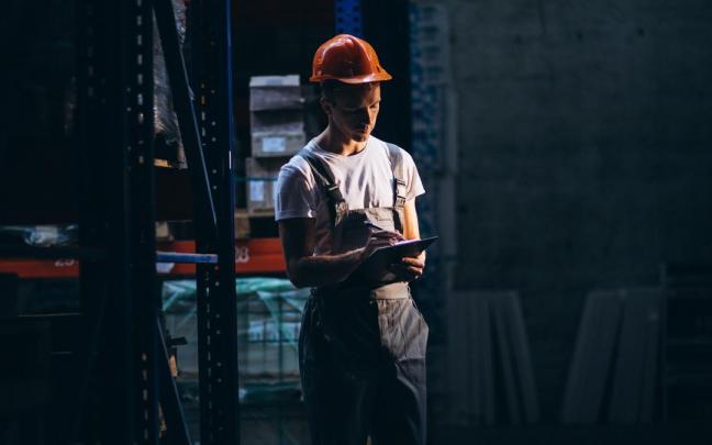 Un trabajador toma notas en un bloc durante un turno de noche.