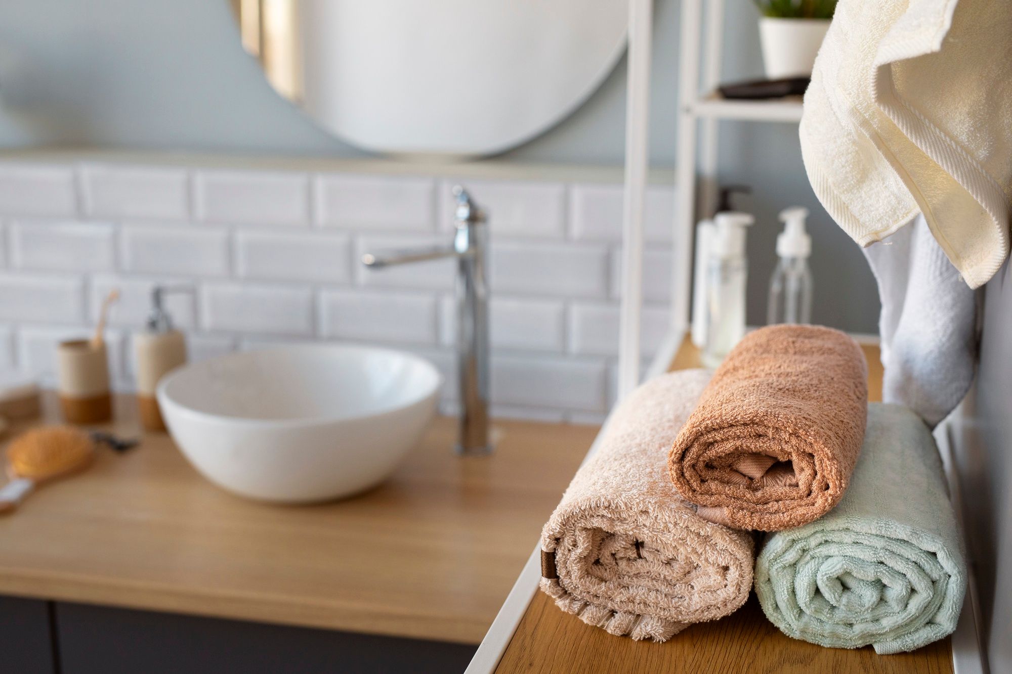 Tres toallas de lavabo enrolladas sobre una encimera del baño.