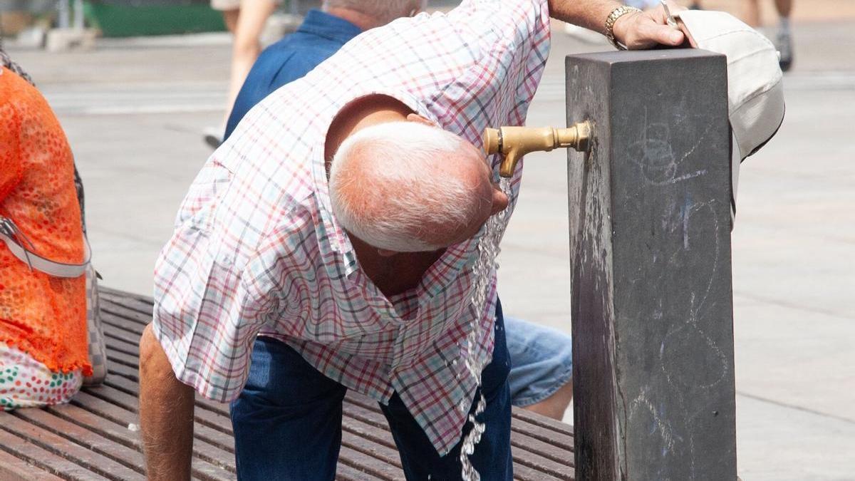 Un hombre se refresca en una fuente debido al calor.