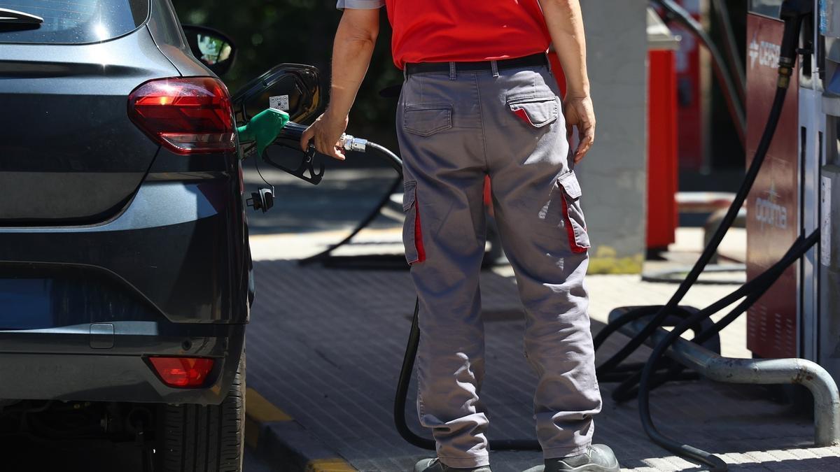 Una persona reposta gasolina en un coche, en una gasolinera.