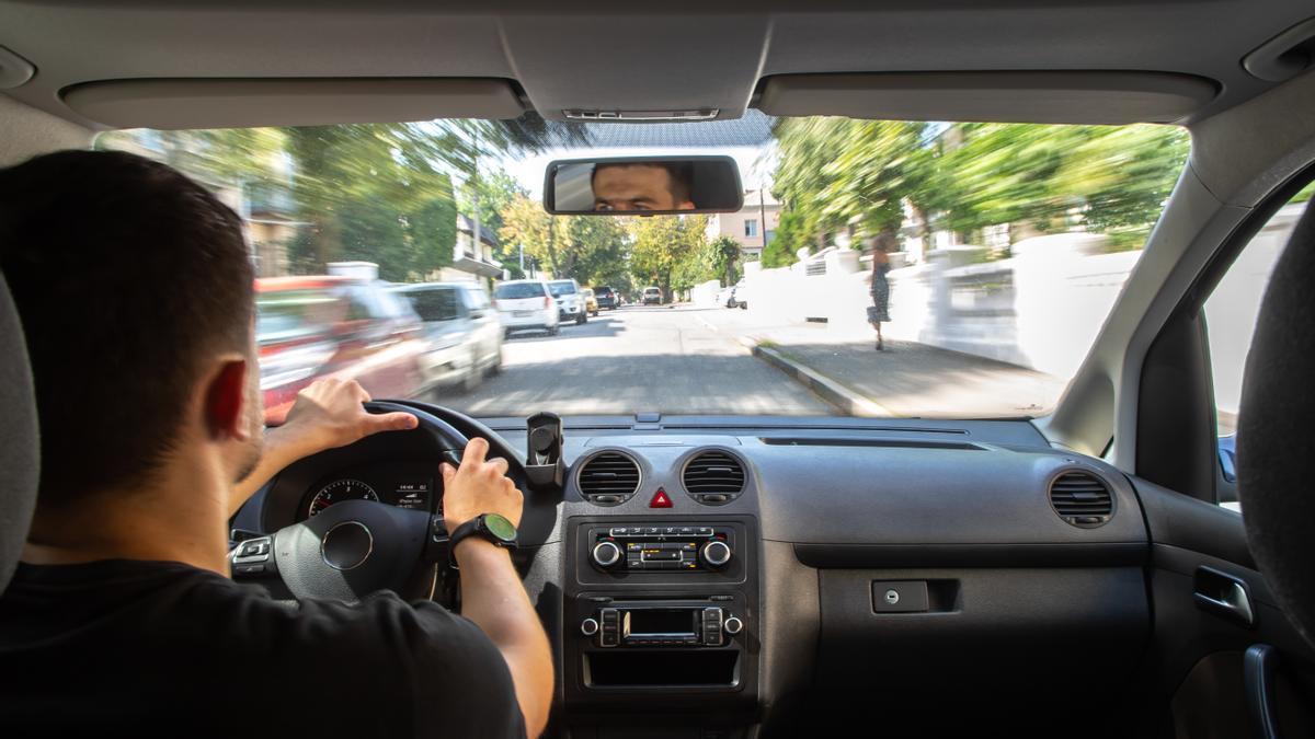 Un hombre circula con su coche por una ciudad.