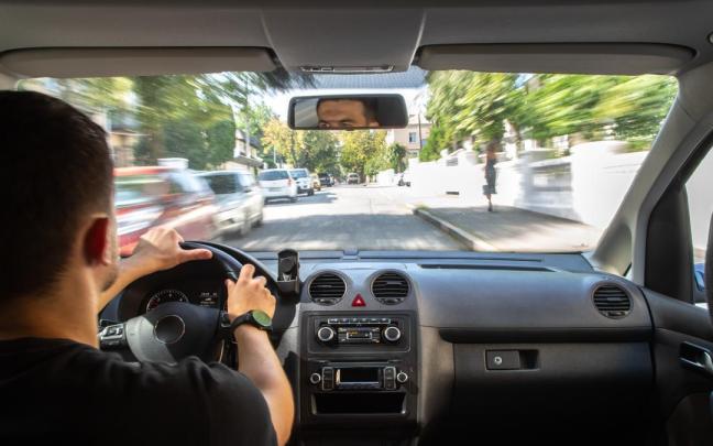 Un hombre circula con su coche por una ciudad.