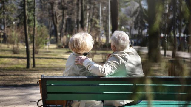Dos personas mayores sentadas en un banco.