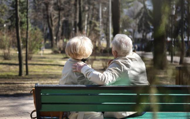 Dos personas mayores sentadas en un banco.