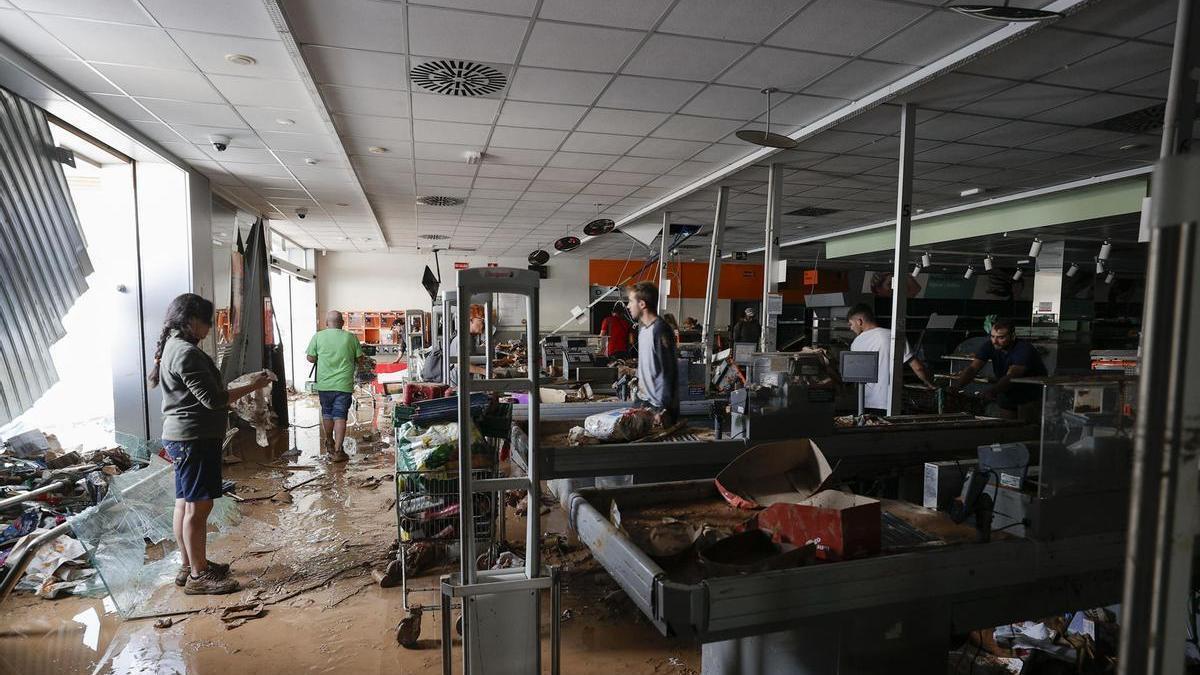 Varias personas intentan recoger alimentos de una tienda de Paiporta.