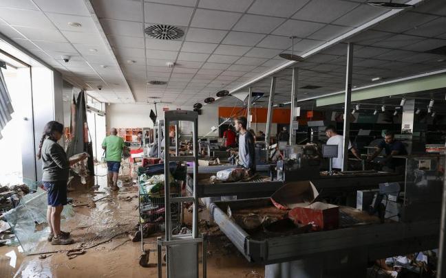 Varias personas intentan recoger alimentos de una tienda de Paiporta.