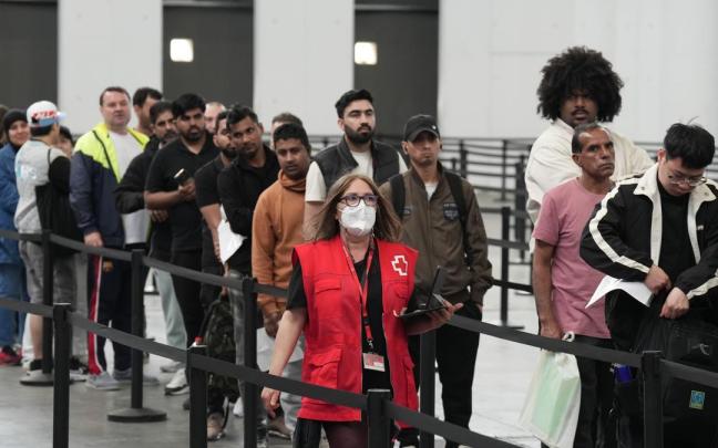 Decenas de migrantes hacen cola en el pabellón 2 del recinto de Montjuïc de Fira de Barcelona.