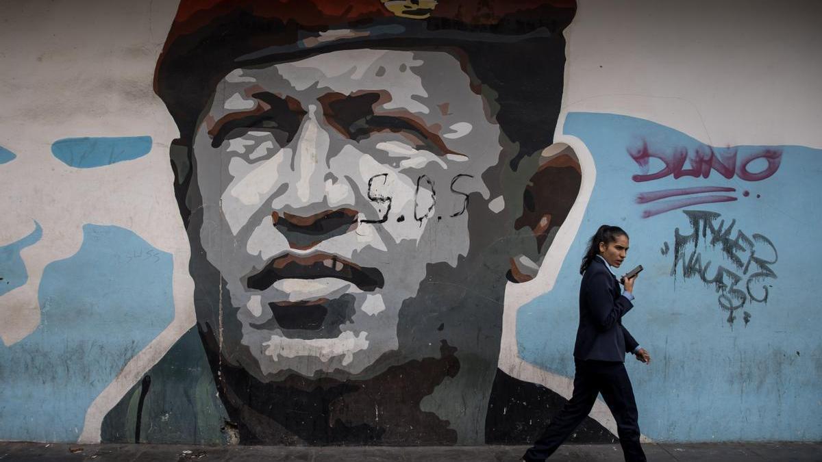 Una mujer pasea ante un mural en memoria de Hugo Chávez.