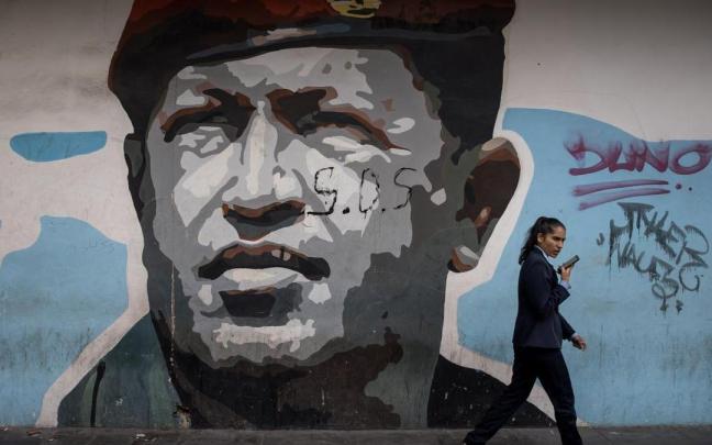 Una mujer pasea ante un mural en memoria de Hugo Chávez. Una mujer pasea ante un mural en memoria de Hugo Chávez.