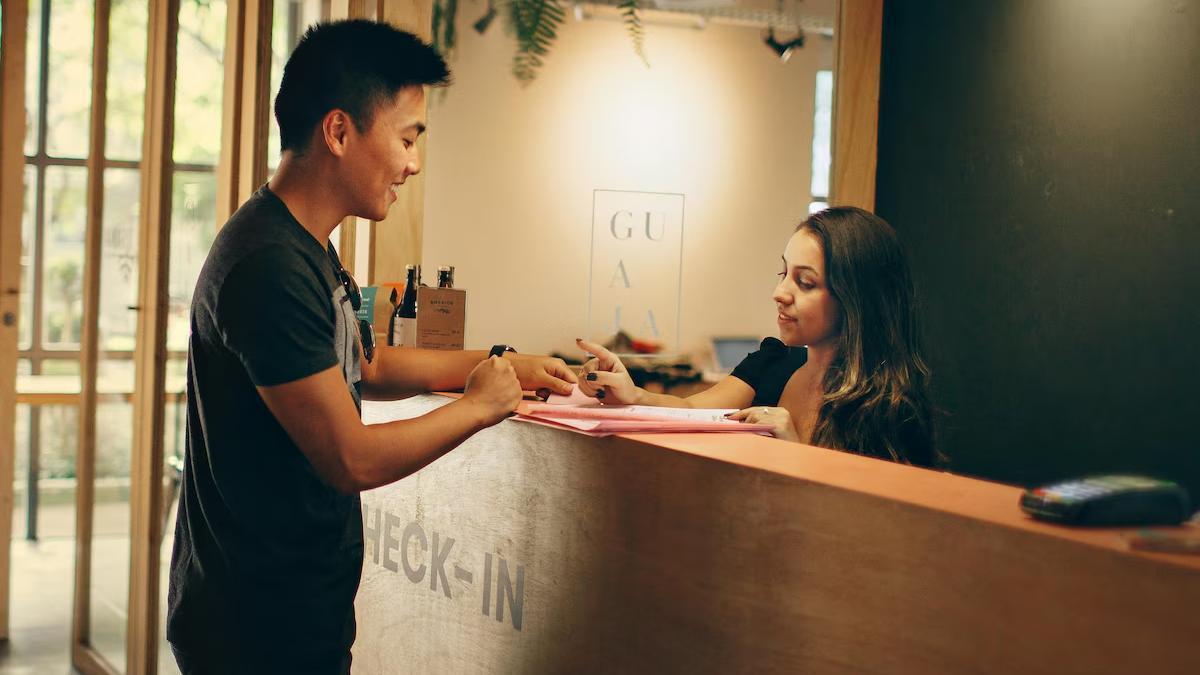 Un turista entrega información privada en la recepción de un hotel Pexels