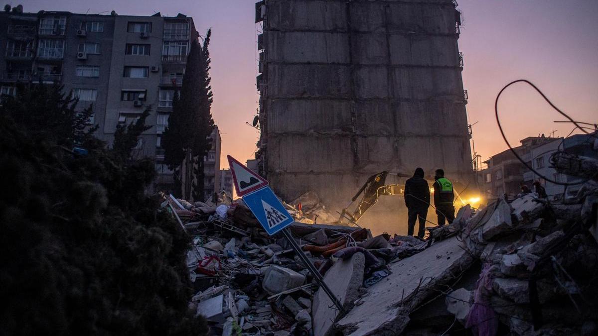 Dos miembros de los equipos de rescate junto a los restos de un edificio derrumbado en Hatay.