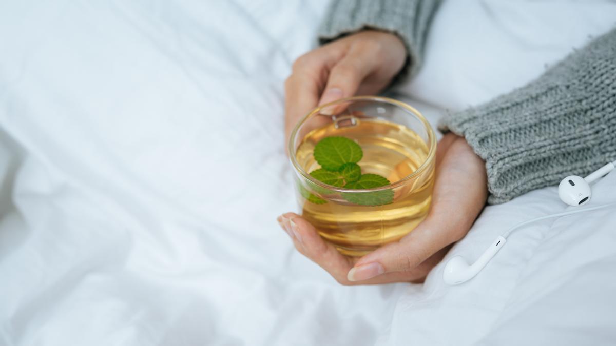 Manos de una chica que sustituye el café por una infusión relajante antes de dormir.