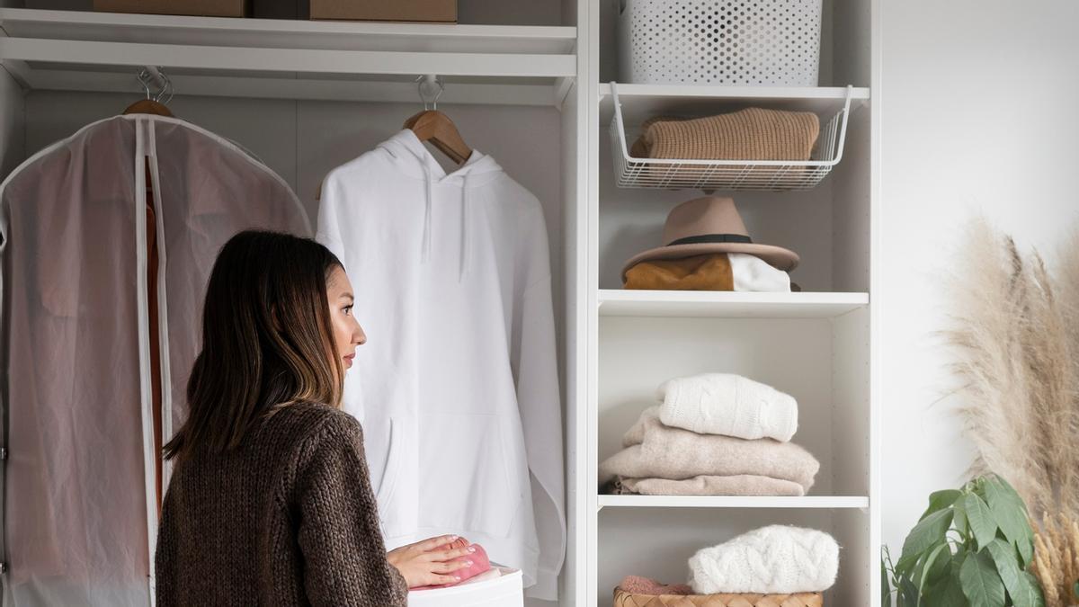 Una mujer ordena la ropa en su armario.