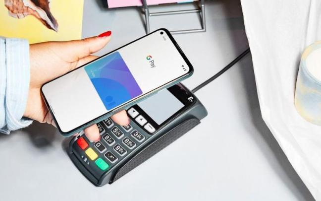 Persona pagando con el móvil y la aplicación de Google Pay. Persona pagando con el móvil y la aplicación de Google Pay.