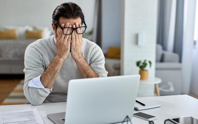 Un hombre, frente al ordenador con pinta de no estar pasándolo bien.