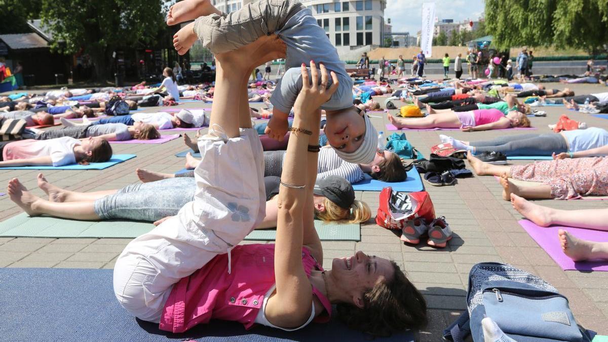 Una mujer comparte ejercicios de yoga con su hijo en una sesion conjunta con otras mujeres.