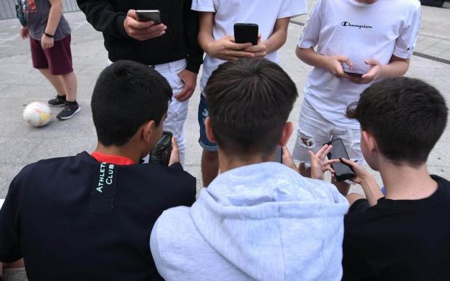 Un grupo de jóvenes miran sus teléfonos móviles Un grupo de jóvenes miran sus teléfonos móviles