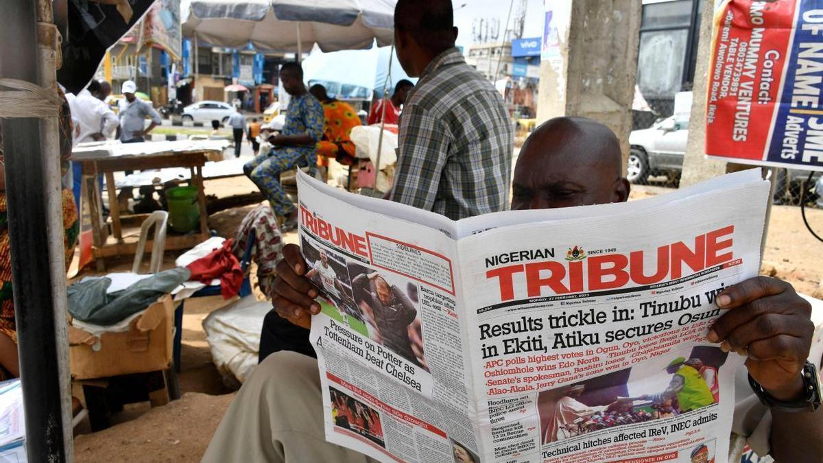 Un hombre lee los resultados de las elecciones de Nigeria en un periódico.