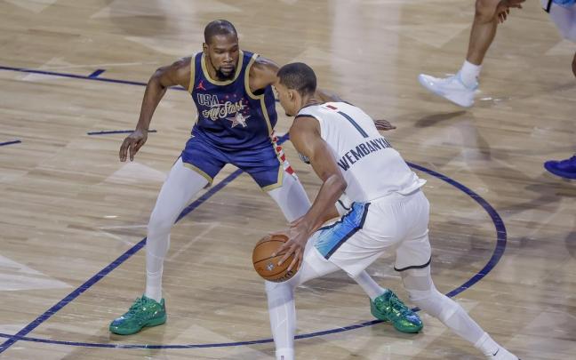 Victor Wembanyama, con el balón, frente a Kevin Durant.