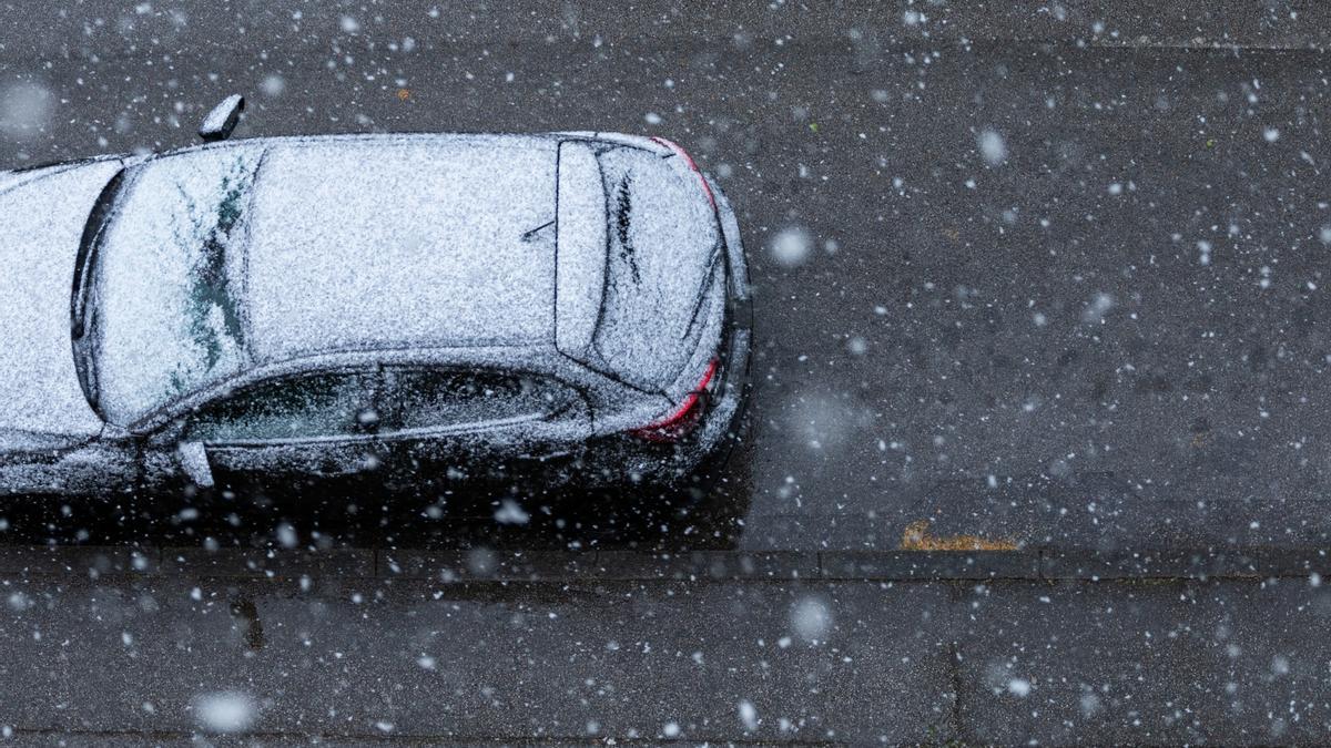 Un coche, circulando durante una nevada.