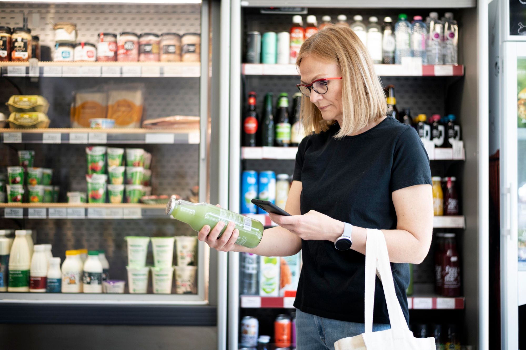 Una mujer, delante de una cámara con lácteos y otros alimentos refrigerados.