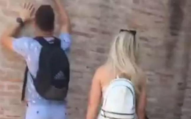 El joven escribiendo su nombre y el de su novia en el Coliseo.