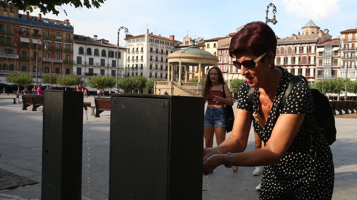 Una mujer bebe agua en una de las fuentes de la plaza del Castillo. JAVIER BERGASA