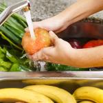 Una persona lavando un tomate