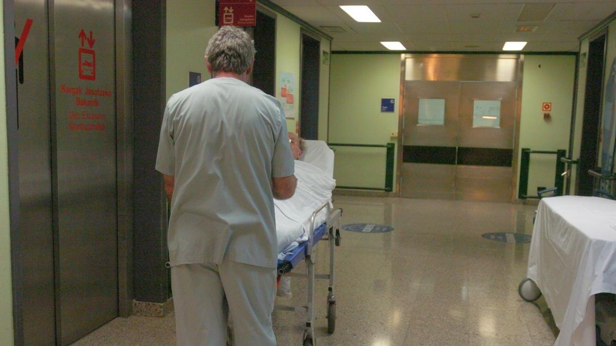 Un celador lleva a un paciente en camilla en un hospital de la red pública vasca.