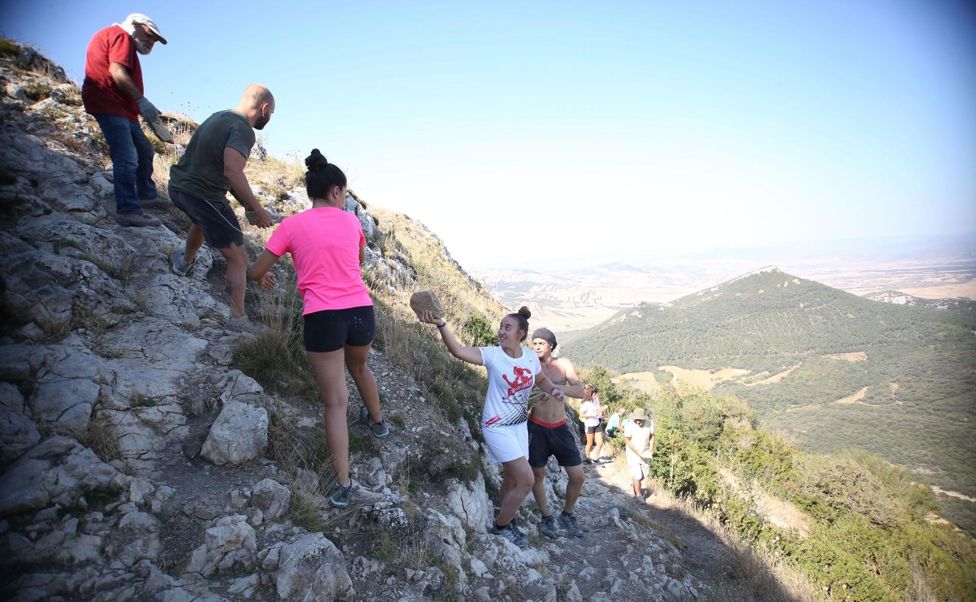 Cadena humana para subir piedras desde la ladera de la peña hasta la cima.