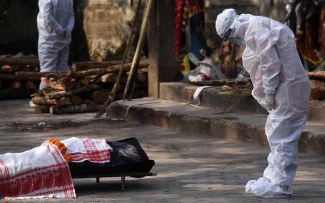Un familiar de una víctima de covid en la India, antes de una cremación.