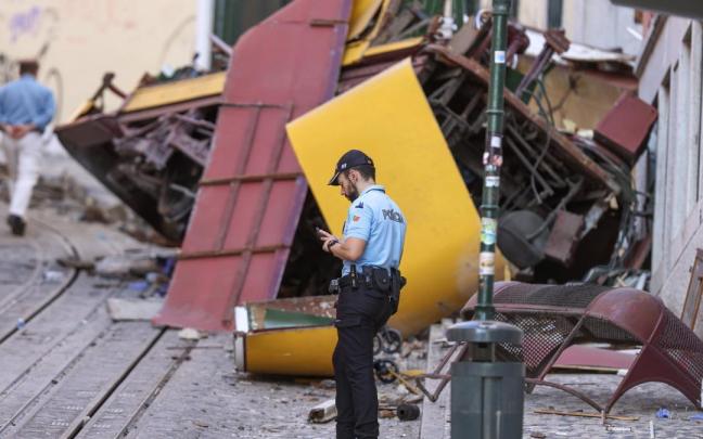 Un policía junto a los restos del Elevador de Gloria descarrilado en Lisboa