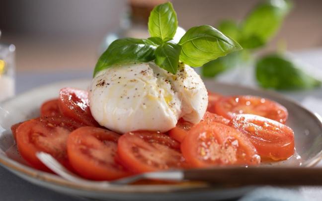 Una ensalada de tomate con burrata y albahaca.